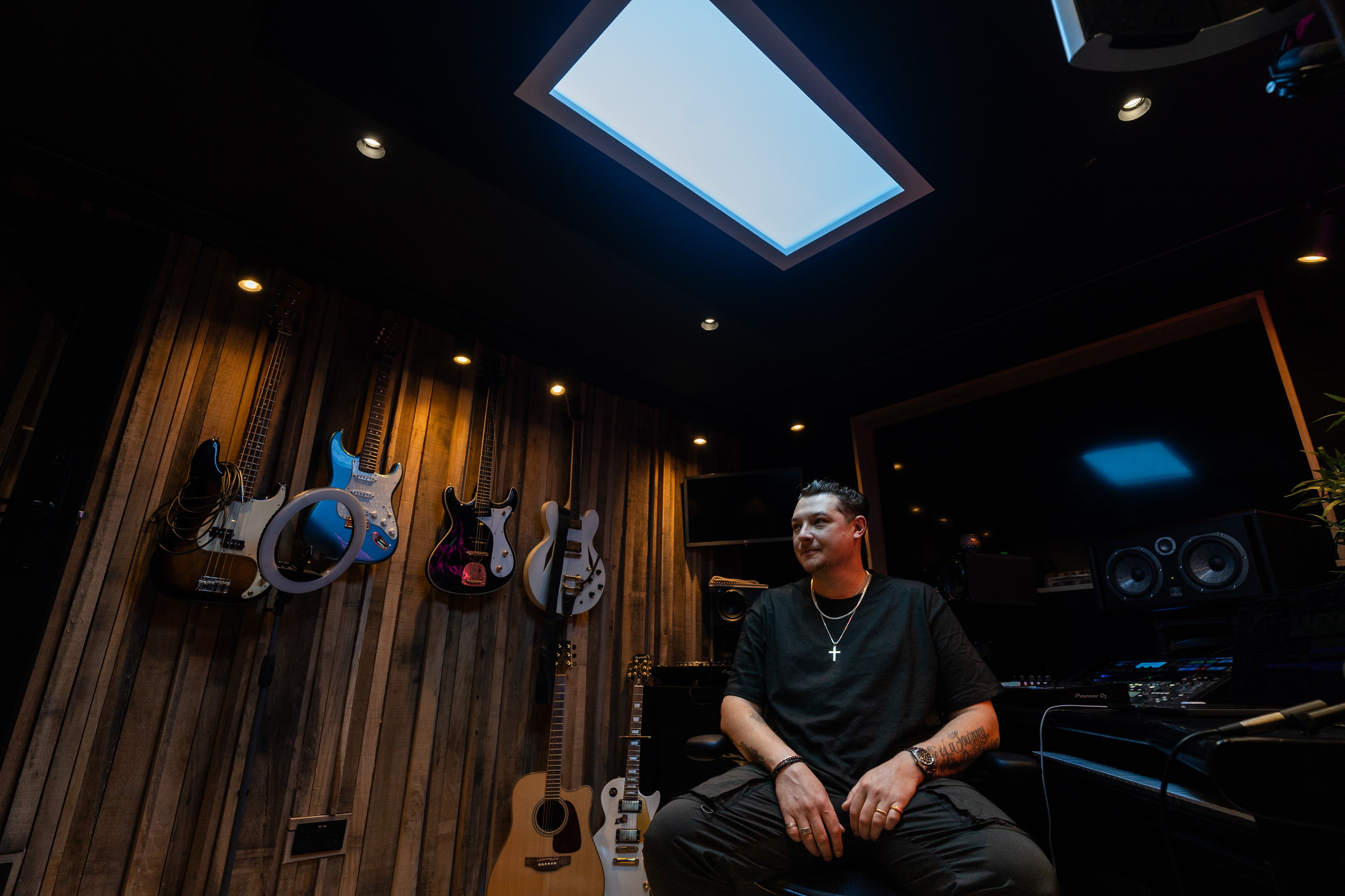 Innerscene Virtual Sun installation case study with the acclaimed British singer, songwriter, and record producer John Newman sitting in his studio with guitars, speakers, and other musical equipment