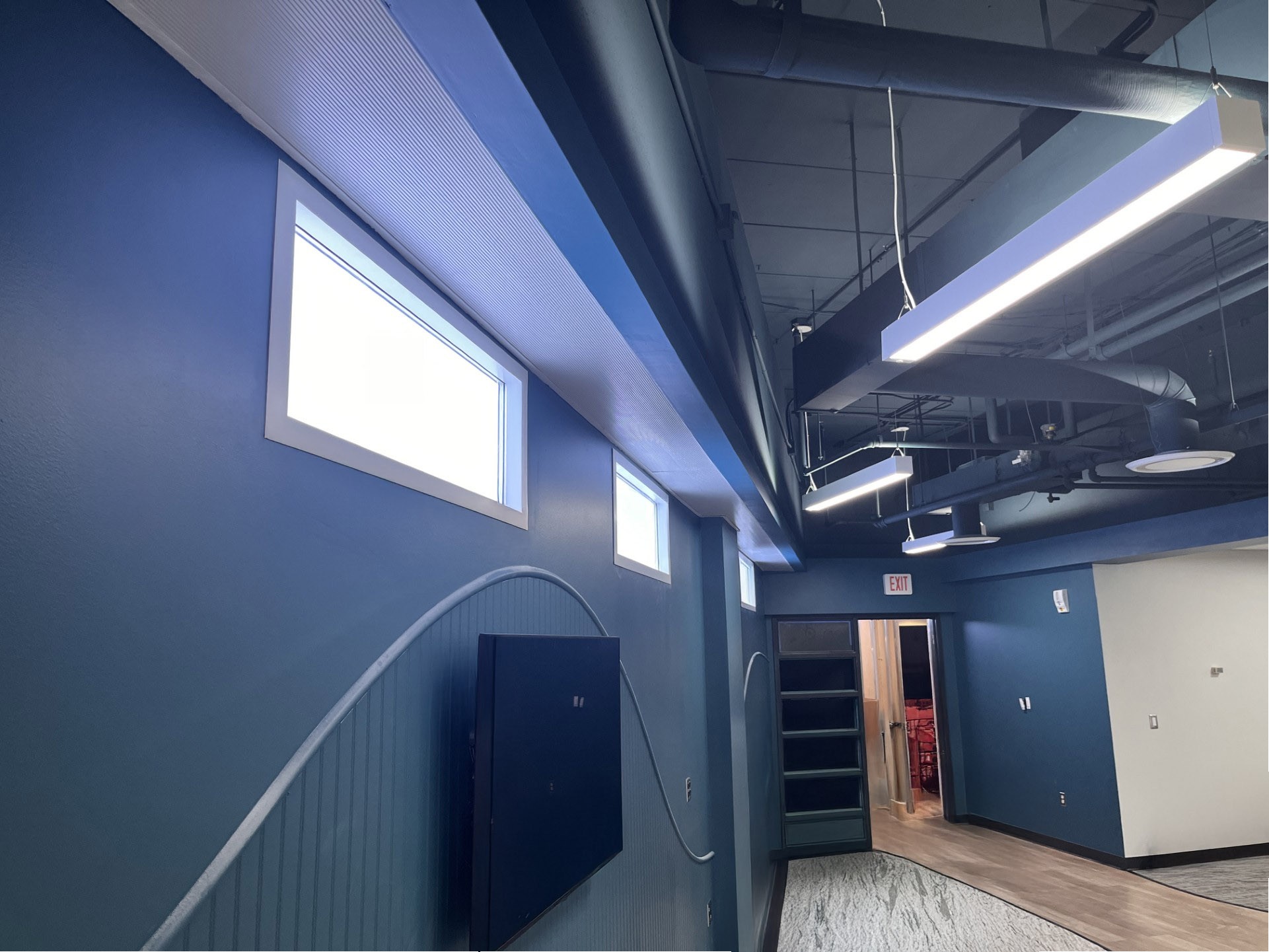 Circadian Sky panels wall-mounted as windows in a commercial space with blue walls and exposed ceiling