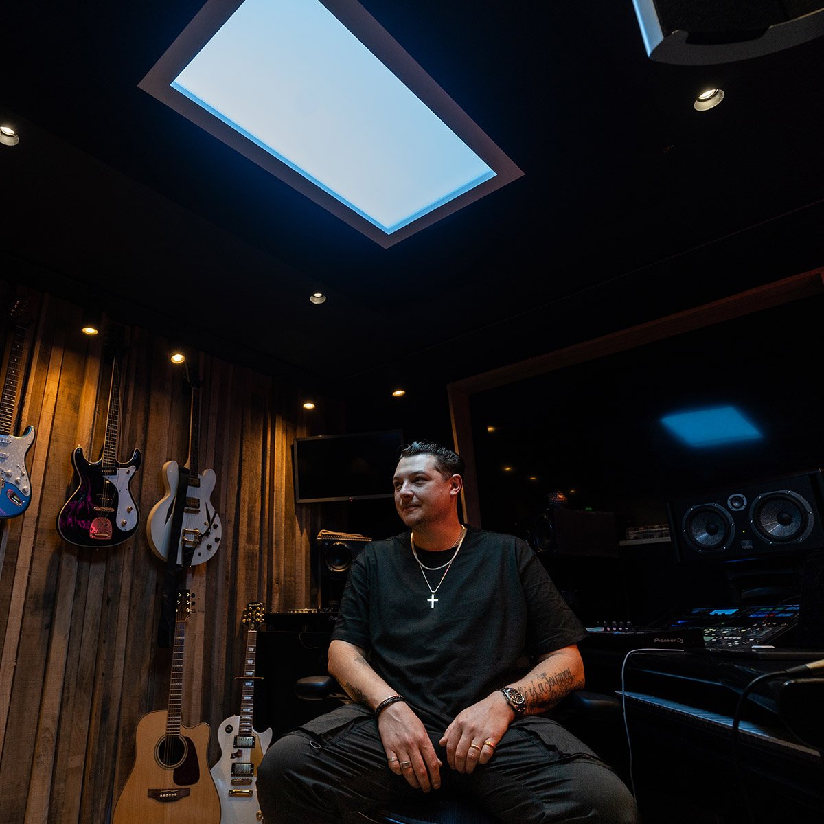 Innerscene Virtual Sun installation case study preview with the acclaimed British singer, songwriter, and record producer John Newman sitting in his studio with guitars, speakers, and other musical equipment